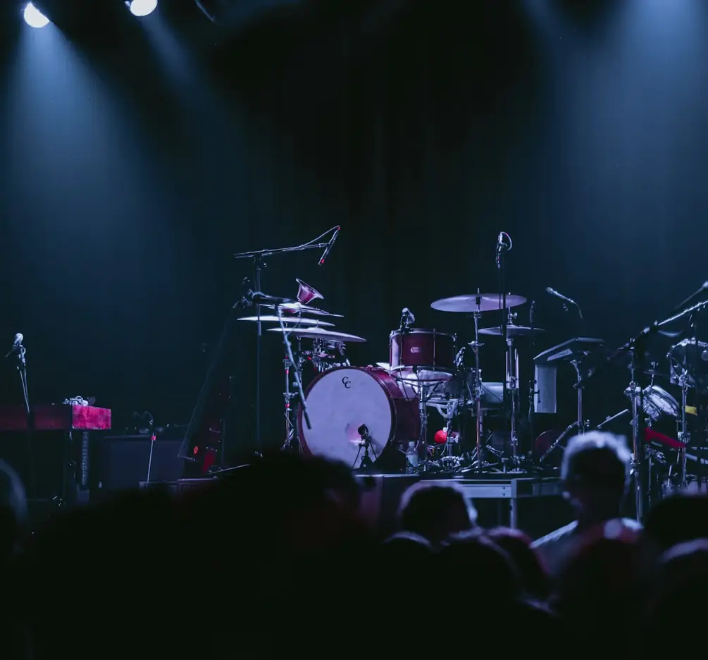 Scène de concert éclairée en bleu avec une batterie