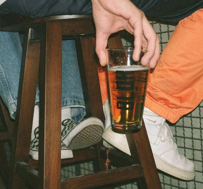 Verre de bière pression tenu au-dessus d’un tabouret